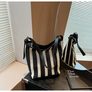 Detail of black and white striped knit hobo bag with sleek leather strap in modern setting