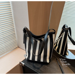 Detail of the black and white striped mesh tote bag with black leather strap and metal buckle