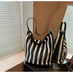 Close-up of black and white striped tote bag with mesh texture and leather handles