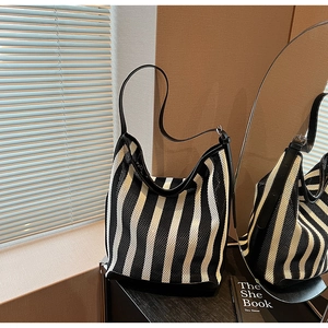 Detail of black and white striped knit shoulder bag featuring premium leather straps