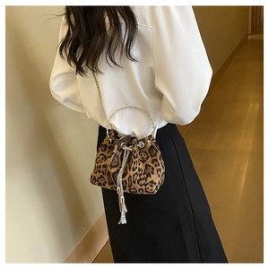 Leopard print bucket bag with metal ring handle shown on a model in a modern indoor setting