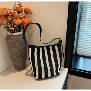 Detail of black and white striped shoulder bag with mesh hollow texture on white surface