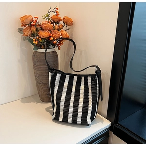 Detail of minimalist black and white striped shoulder bag with leather trim and mesh texture