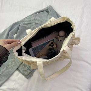 Cream canvas bucket tote bag with ruffled edges featuring spacious interior for daily essentials