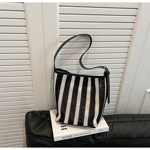 Detail of black and white striped mesh tote bag featuring premium leather strap and hardware