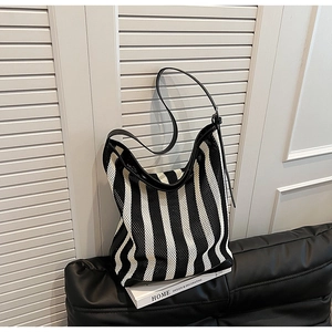 Macro shot of striped knit hobo bag featuring black leather trim and textured mesh material