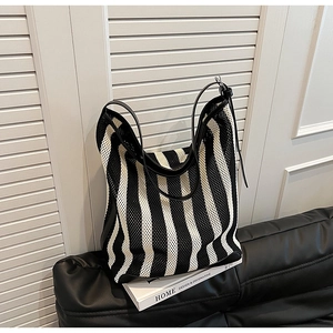 Detail of black and white striped mesh tote bag with premium leather trim on padded seat