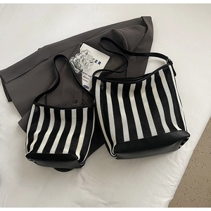 Detail of mesh tote bag in black and white stripes with durable leather base and straps
