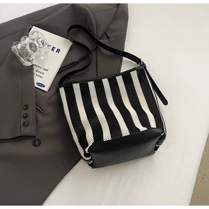 Detailed view of the striped bucket bag featuring black leather trim and woven knit texture