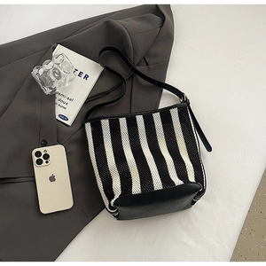 Detail of black and white striped knit bucket bag with premium leather base and strap