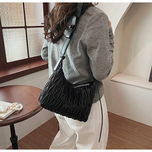 Detail of black pleated leather underarm bag with adjustable strap and silver zipper