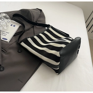 Detail of striped knit shoulder bag showing premium texture contrast and leather base