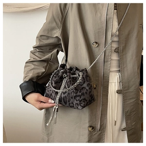 Detail of leopard print bucket bag with silver chain and fringe tassel on a model