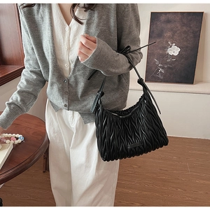 Detail of black matelassé pleated leather hobo bag with a knotted shoulder strap