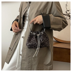 Detail of leopard print bucket bag featuring silver circular handle and tassel chain