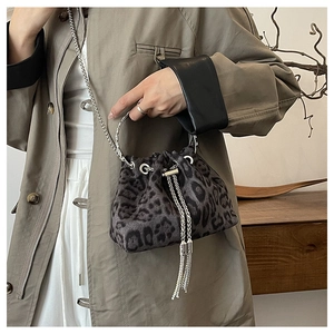 Detail of leopard print bucket bag featuring silver ring handle and metal chain strap