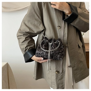 Detailed view of leopard print bucket bag with silver chains on a khaki coat outfit