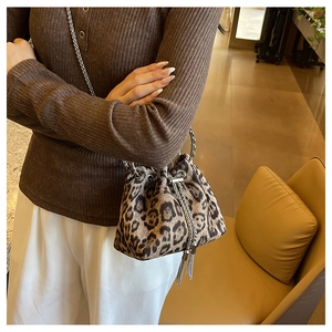 Detail of leopard print bucket bag with silver chain strap and drawstring closure on model