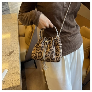 Close-up of leopard print bucket bag with silver metal handle and chain strap in cafe
