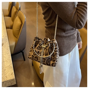 Leopard print bucket bag with gold chain strap and metal fringe detail in a cozy setting