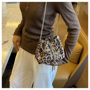 Detail of leopard print bucket bag featuring silver ring handle and metal tassel accents