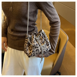 Detail of leopard bucket bag with silver metal handle and fringe tassel on knit outfit