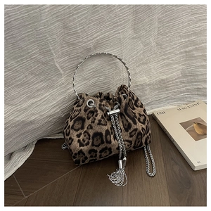 Detail of leopard print bucket bag with metal ring handle and chain fringe on wood floor