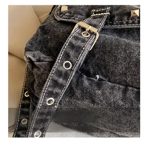 Detail of vintage washed black denim bag with silver hardware and contrast stitching