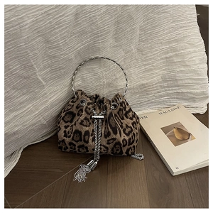Detail of leopard print bucket bag with metal ring handle and chain on wooden floor