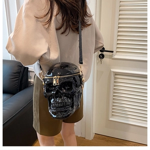Vue de dos d'un modèle portant un sac bandoulière tête de mort en cuir verni noir brillant