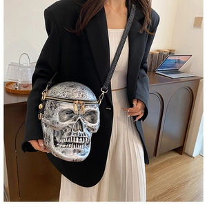 Close-up of a silver skull crossbody bag styled with a black blazer and white skirt