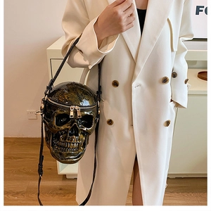 Détail du sac à bandoulière crâne vert sur mannequin portant un manteau blanc à double boutonnage