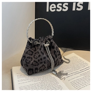 Detail of leopard print bucket bag with silver ring handle and tassel on open book