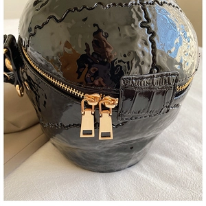 Détail de la surface en cuir verni noir brillant avec fermeture éclair dorée du sac