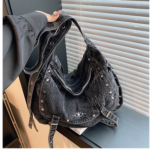 Detail of Y2K denim hobo bag featuring silver rivets, zippers, and eye embroidery