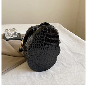 Détails du cuir verni crocodile et des crochets dorés sur le sac en forme de crâne