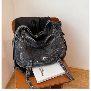 Detail of vintage washed denim tote bag with rivets and eye embroidery on wooden chair