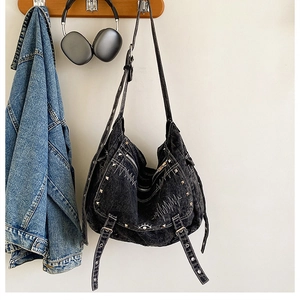 Detail of vintage washed black denim bag with silver studs, zippers, and eye embroidery