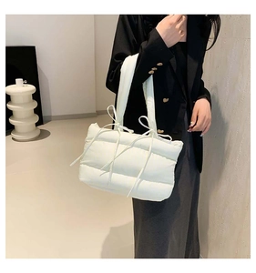 Détail du sac bandoulière matelassé blanc avec nœud décoratif et texture moelleuse