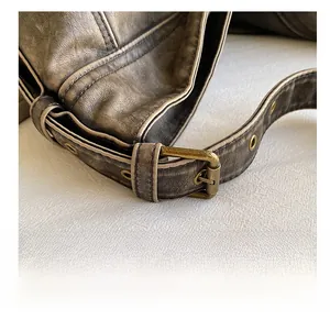 Detail of vintage washed PU leather bag showing antique bronze buckle and stitched strap