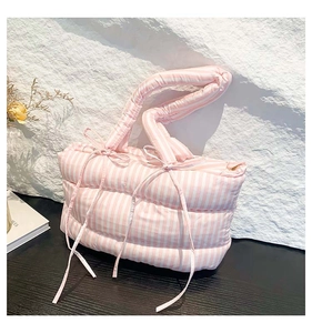 Détail du sac cabas matelassé à rayures roses et blanches avec des nœuds décoratifs