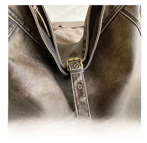 Detail of vintage brass buckle and eyelet strap on brown washed PU leather shoulder bag