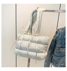 Détail du sac cabas matelassé à rayures avec des nœuds décoratifs sur la bandoulière