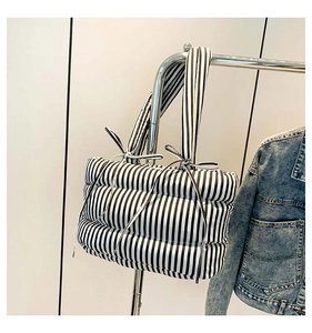 Détail d'un sac cabas matelassé à rayures noires et blanches avec nœuds décoratifs