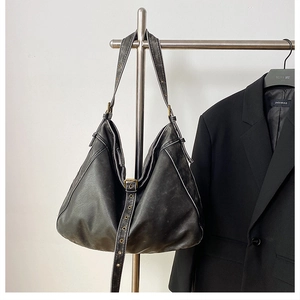 Detail of vintage washed PU leather shoulder bag with adjustable metal buckle strap