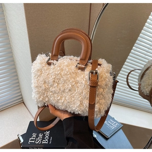 Detail of white plush faux fur texture with contrast brown leather handles on a boston bag