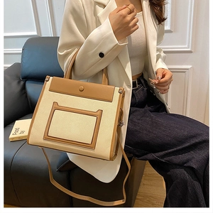 Detail showing high-quality canvas and brown leather stitching on a trapezoid handbag