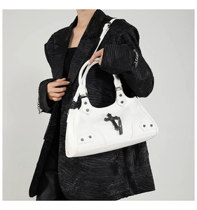 Detail einer weißen Gothic-Punk-Tasche mit schwarzem Kreuzanhänger und Silbernieten