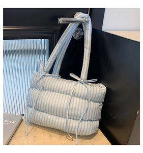 Détail du sac cabas matelassé à rayures bleues et blanches avec nœuds latéraux