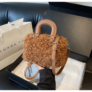 Detailed macro view of plush teddy fabric and brown leather handle on Boston bag